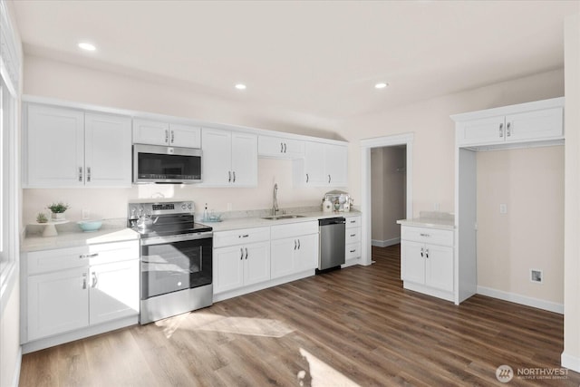 kitchen featuring a sink, stainless steel appliances, wood finished floors, and white cabinetry