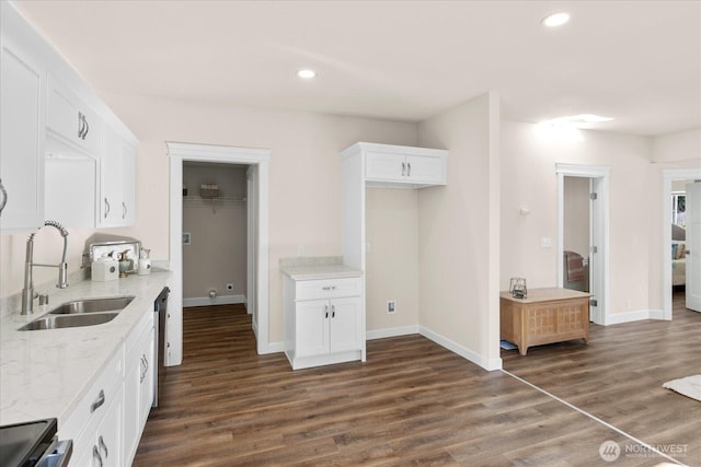 kitchen featuring dishwashing machine, dark wood-style floors, light stone countertops, and a sink