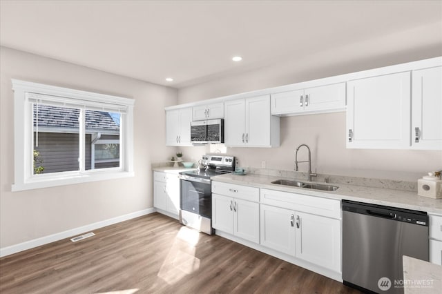 kitchen with visible vents, a sink, white cabinetry, stainless steel appliances, and baseboards