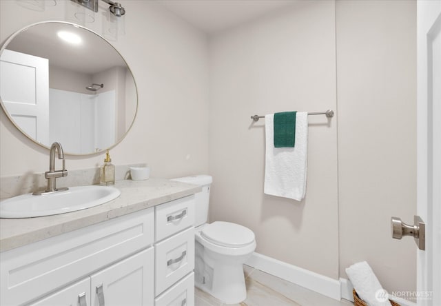 bathroom with baseboards, toilet, and vanity