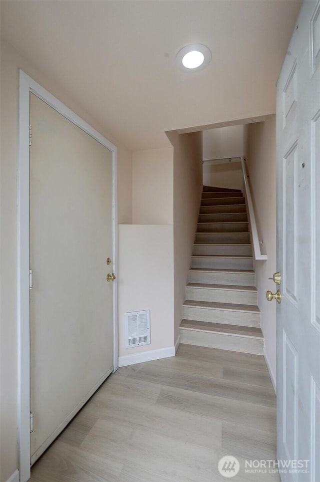 stairway with visible vents, baseboards, and wood finished floors