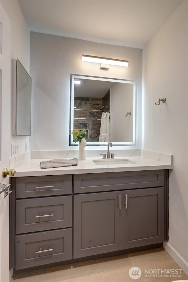 bathroom featuring vanity, a shower with shower curtain, and baseboards