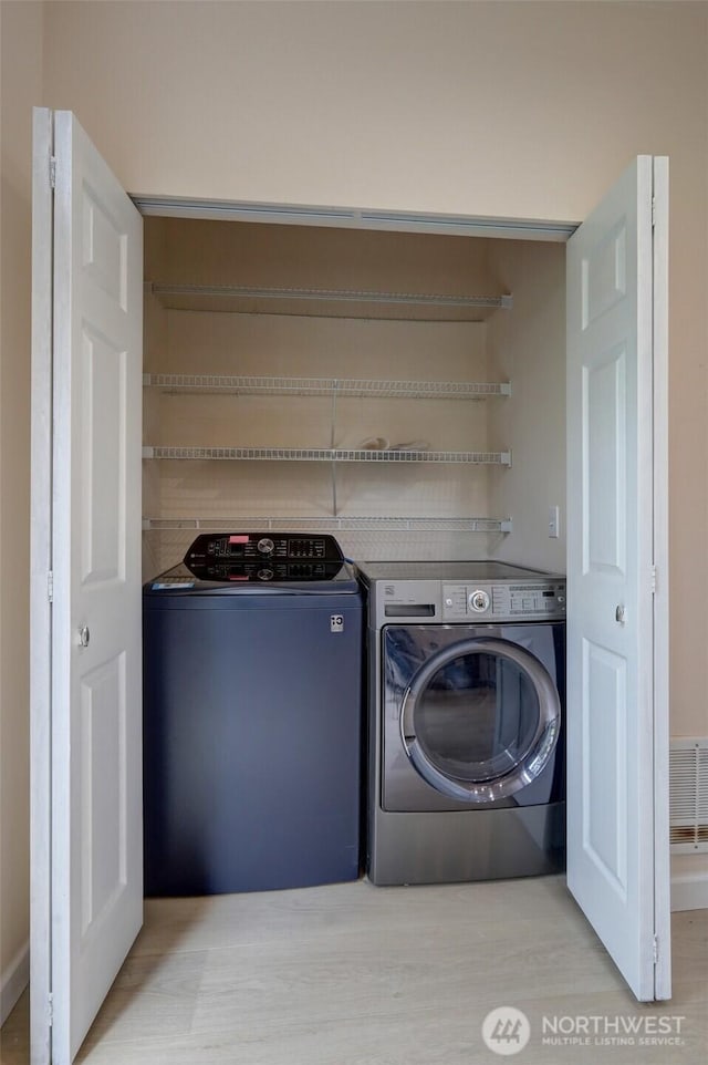 washroom with laundry area, separate washer and dryer, and visible vents