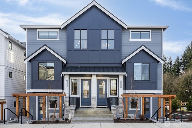 view of front of home featuring metal roof, stone siding, board and batten siding, and a standing seam roof