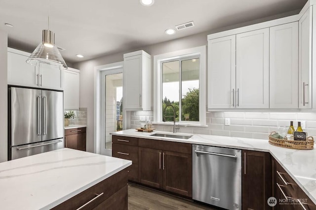 kitchen featuring dark brown cabinetry, visible vents, stainless steel appliances, and a sink