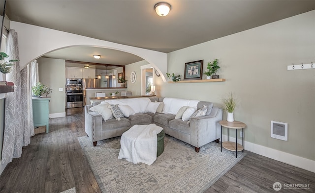 living room featuring baseboards, arched walkways, and dark wood-type flooring