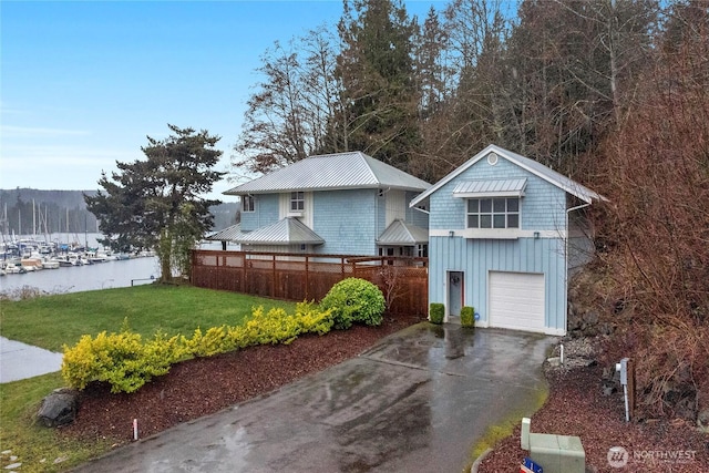 view of front of property featuring board and batten siding, fence, a front yard, a garage, and driveway