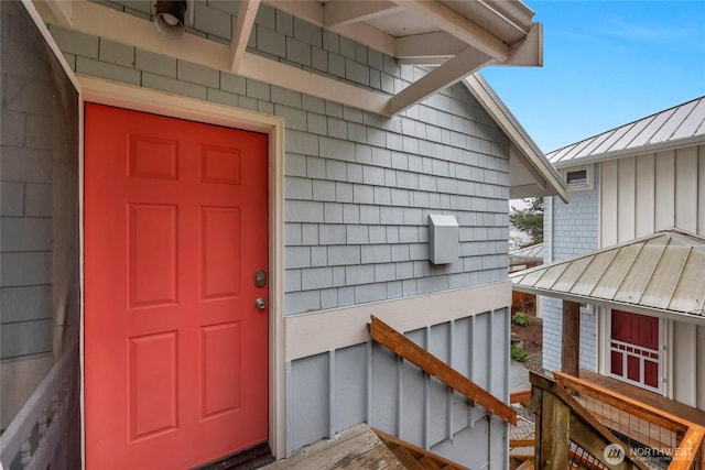 view of exterior entry with a standing seam roof, board and batten siding, and metal roof