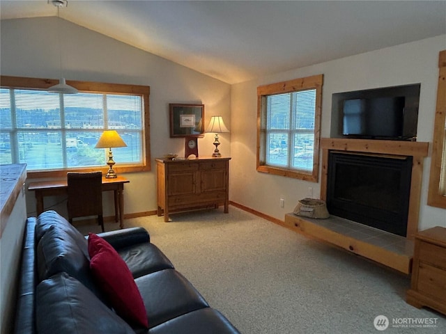 carpeted living area with a fireplace with raised hearth, baseboards, and lofted ceiling