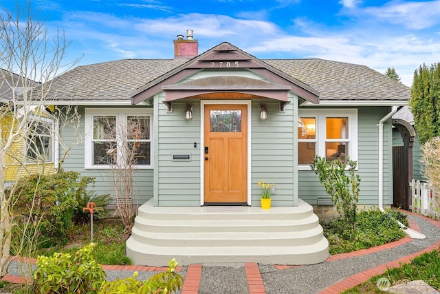 property entrance with a chimney and a shingled roof