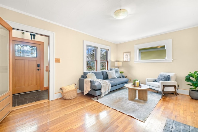 living area featuring baseboards, ornamental molding, and light wood finished floors