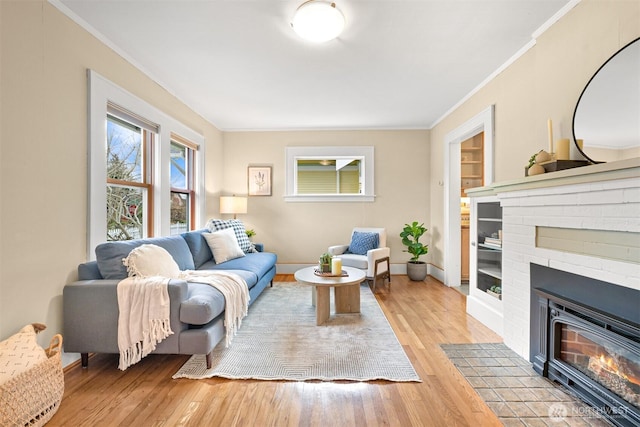 living room with light wood-style flooring, a fireplace, baseboards, and ornamental molding