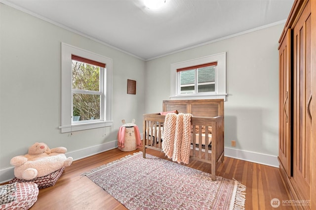 bedroom featuring baseboards, wood finished floors, and crown molding