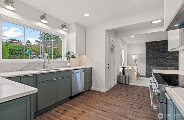 kitchen featuring dark wood finished floors, backsplash, appliances with stainless steel finishes, and a sink