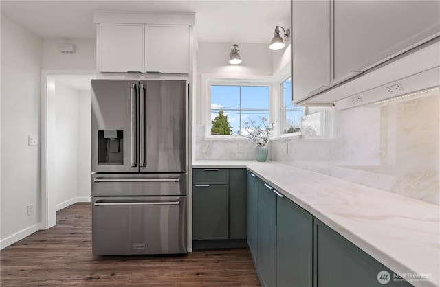 kitchen with light stone countertops, dark wood-type flooring, white cabinetry, high quality fridge, and backsplash