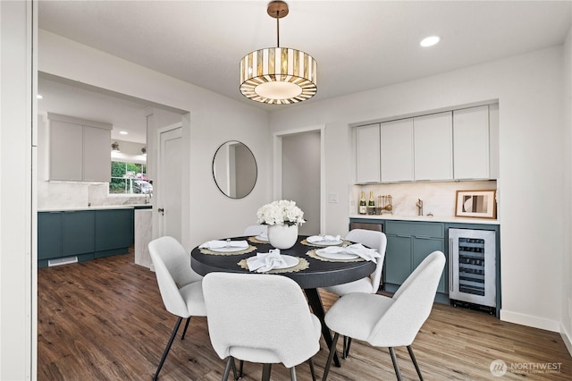 dining room with wood finished floors, beverage cooler, baseboards, and indoor bar