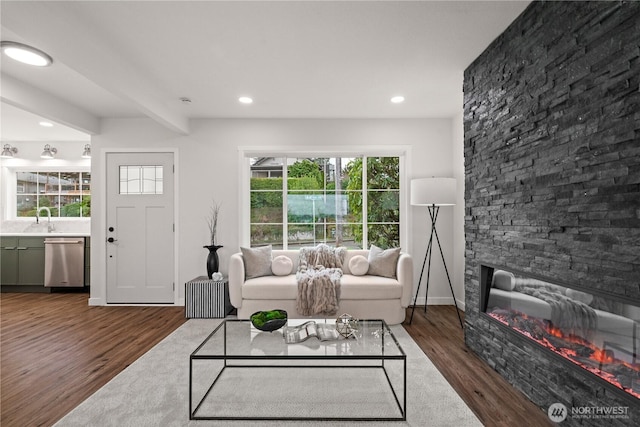 living area with recessed lighting, beamed ceiling, wood finished floors, and a fireplace