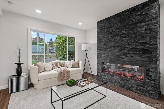 living room with a stone fireplace, recessed lighting, baseboards, and wood finished floors