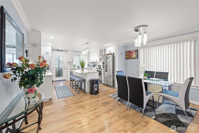 dining space featuring recessed lighting, light wood-type flooring, ornamental molding, and a chandelier