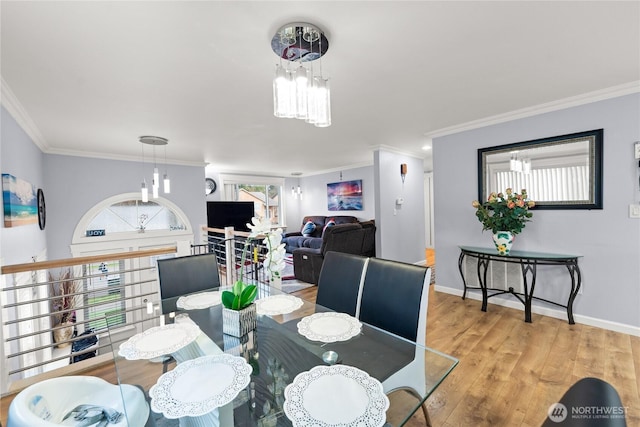 dining area with a chandelier, ornamental molding, baseboards, and wood finished floors