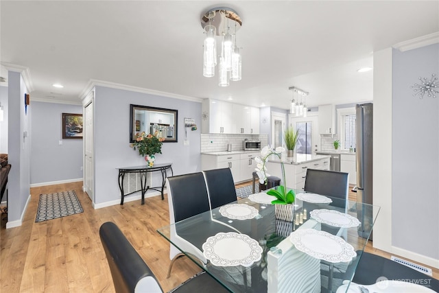 dining space featuring crown molding, baseboards, a chandelier, recessed lighting, and light wood-style flooring