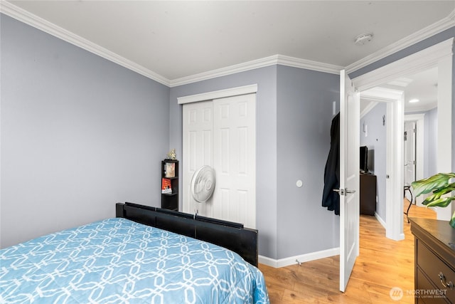 bedroom with a closet, baseboards, light wood finished floors, and ornamental molding