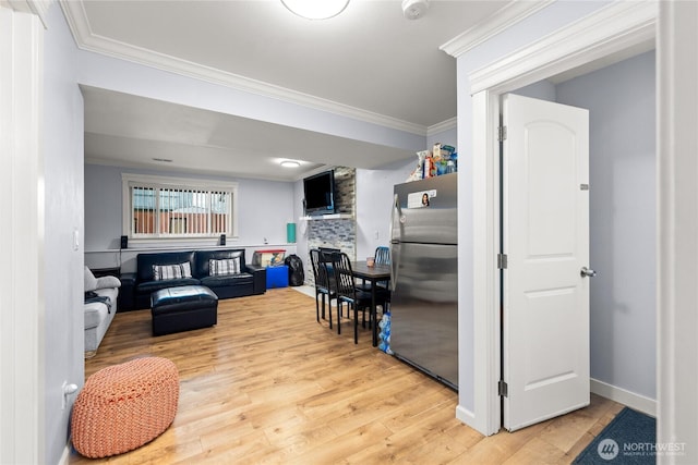 living area featuring light wood-style flooring, baseboards, a stone fireplace, and ornamental molding