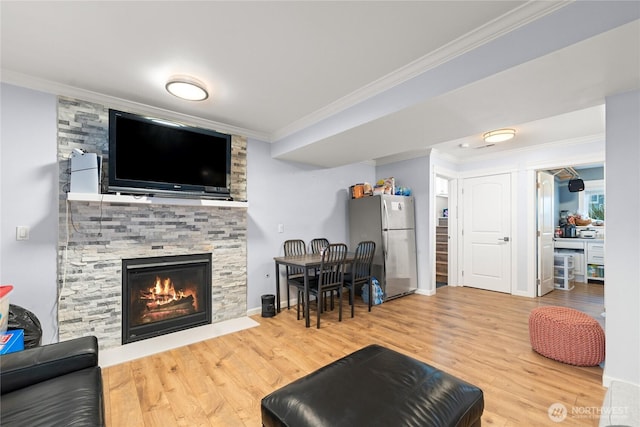 living area with baseboards, a fireplace, wood finished floors, and crown molding