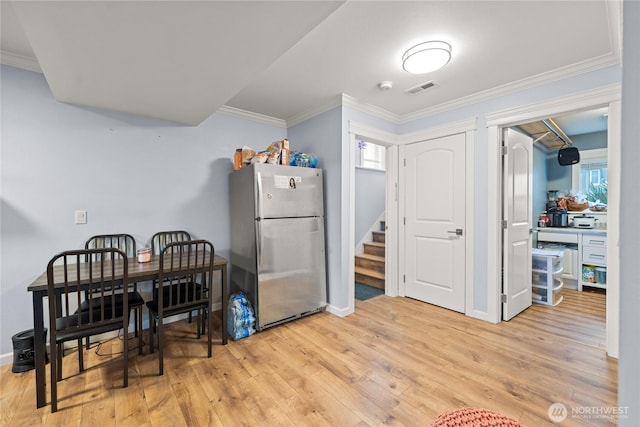 kitchen with light wood finished floors, visible vents, freestanding refrigerator, and ornamental molding