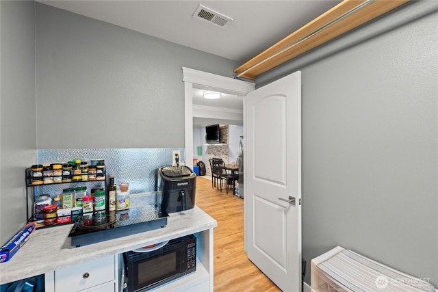 kitchen featuring light countertops, light wood-style flooring, visible vents, and black microwave