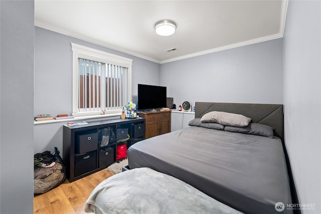 bedroom featuring visible vents, crown molding, and light wood finished floors