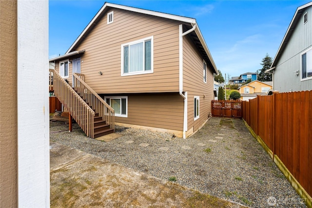 back of property featuring stairs and a fenced backyard