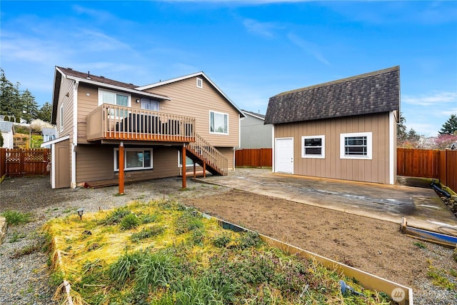 rear view of property featuring a wooden deck, an outdoor structure, a fenced backyard, and stairs