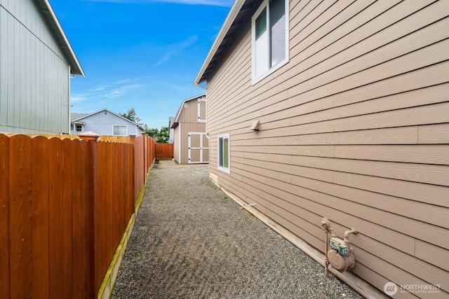 view of home's exterior with an outdoor structure, fence, and a shed