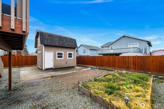 view of yard featuring a patio area, a fenced backyard, a garden, an outbuilding, and a storage unit