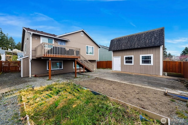 back of property featuring a wooden deck, an outbuilding, and a fenced backyard