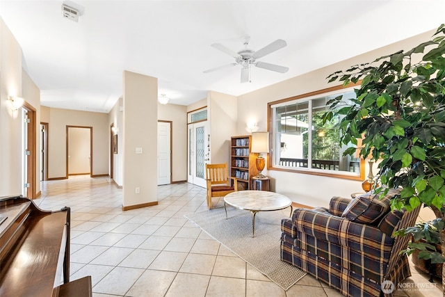 living area with light tile patterned flooring, baseboards, and ceiling fan