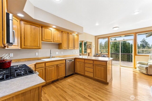 kitchen with light countertops, light wood-style flooring, appliances with stainless steel finishes, and a sink