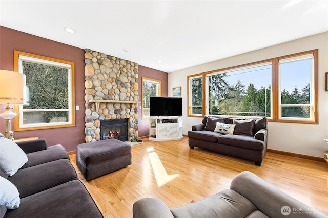 living area featuring a stone fireplace, recessed lighting, baseboards, and wood finished floors