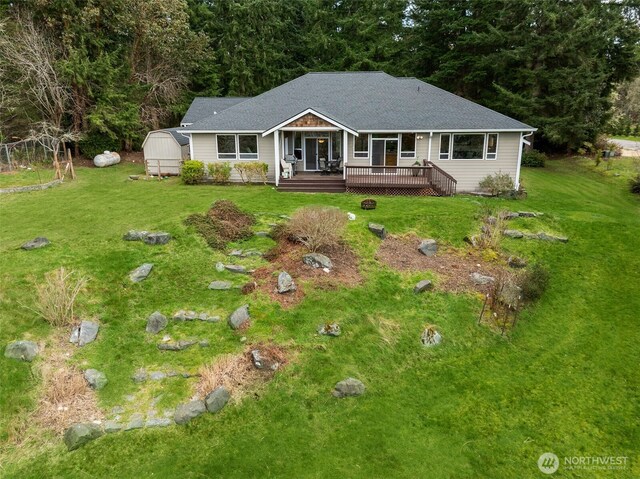 ranch-style home with an outdoor structure, a front lawn, and roof with shingles