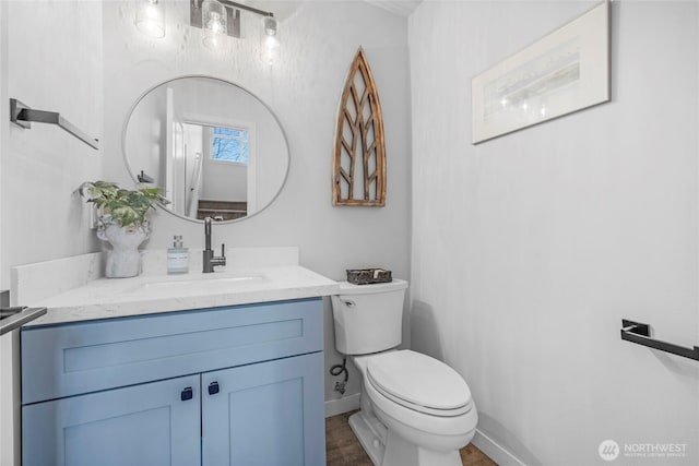 half bath featuring vanity, toilet, and baseboards