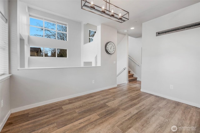 interior space featuring stairway, wood finished floors, baseboards, an inviting chandelier, and recessed lighting