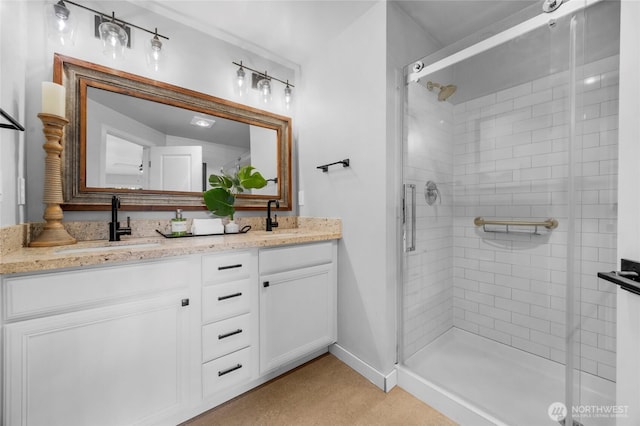 bathroom featuring double vanity, a stall shower, baseboards, and a sink