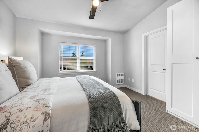 carpeted bedroom with heating unit, baseboards, and ceiling fan