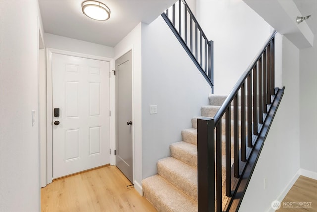 foyer entrance featuring stairway, light wood-style floors, and baseboards