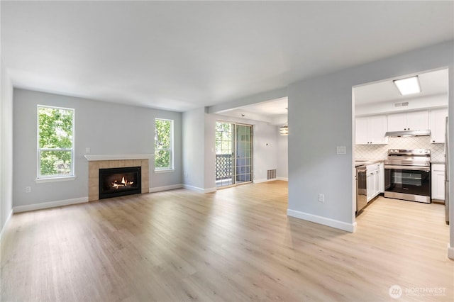 unfurnished living room with a wealth of natural light, visible vents, and light wood-style floors