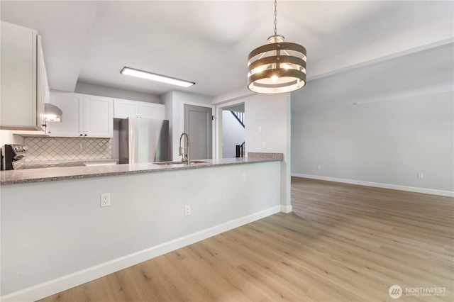 kitchen with light wood finished floors, baseboards, appliances with stainless steel finishes, and a sink