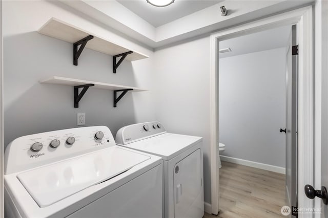 clothes washing area featuring washer and dryer, laundry area, light wood-style floors, and baseboards