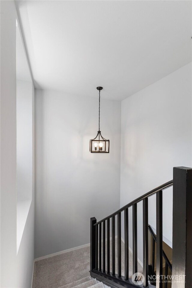 staircase featuring a notable chandelier, carpet flooring, and baseboards