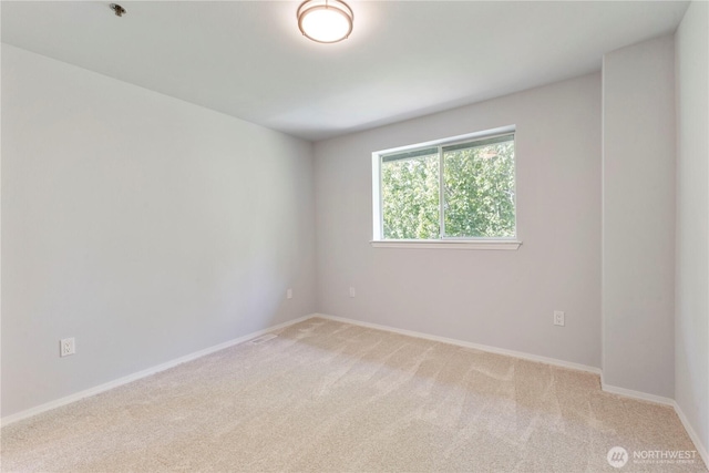 empty room featuring baseboards and light carpet